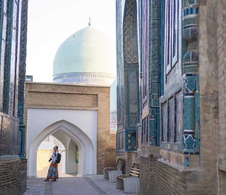 Senior woman on the path between memorial buildings of Shakhi Zinda  Mausoleum which is memorial complex of Islamic architecture from 9 to 12. century in Samarkand, Uzbekistan
1129859652
ancient, architecture, art, asia, building exterior, craft, cultures, decoration, east, entrance, facade, famous place, history, indigenous culture, monument, multi colored, old, pattern, photography, religion, sky, spirituality, travel destinations, unesco world heritage site, mausoleum, silk road, tomb, samarkand, tribal art, central asia, mosaic, ceramics, cemetery, memorial, uzbekistan, tile, turquoise colored, persian culture, photography themes, footpath, single lane road, horizontal, women, one woman only, senior adult, shah-i-zinda
A woman looking up at the memorial buildings of Shah-I-Zinda Mausoleums in Samarkand, Uzbekistan