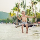 Happy boy sit on swing at the sea shore on sunset.
1197466982