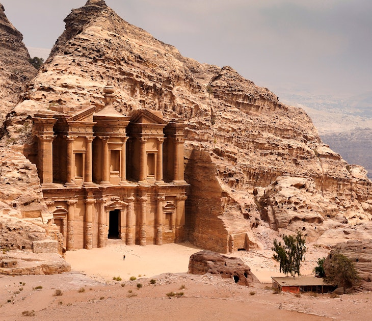 Person stands near the doorway to the Monastery (Ad Deir) in Petra.
972766398
Spirituality, Scenics - Nature, UNESCO World Heritage Site, Architecture, Famous Place, International Landmark, Looking At View, Extreme Terrain, UNESCO, Monument, National Landmark, Petra - Jordan, Stone Material, Tourist, Ma'an Governorate, Building Exterior, Tomb, Archaeology, Sand, Desert, No People, Middle East, Jordan - Middle East, Mountain, Hiding, Middle Eastern Culture, Ancient Civilization, Facade, Monastery, Carving - Craft Product, Large, Travel Destinations, Horizontal, Wadi Musa, Temple - Building, Landscape - Scenery, Red, Al Deir Temple, Cultures, Color Image, Stone - Object, History, Sandstone, Indigenous Culture, Jordan, Ancient, Old, Adventure, Rock - Object, Photography, Built Structure, The Past, Sky, Nature