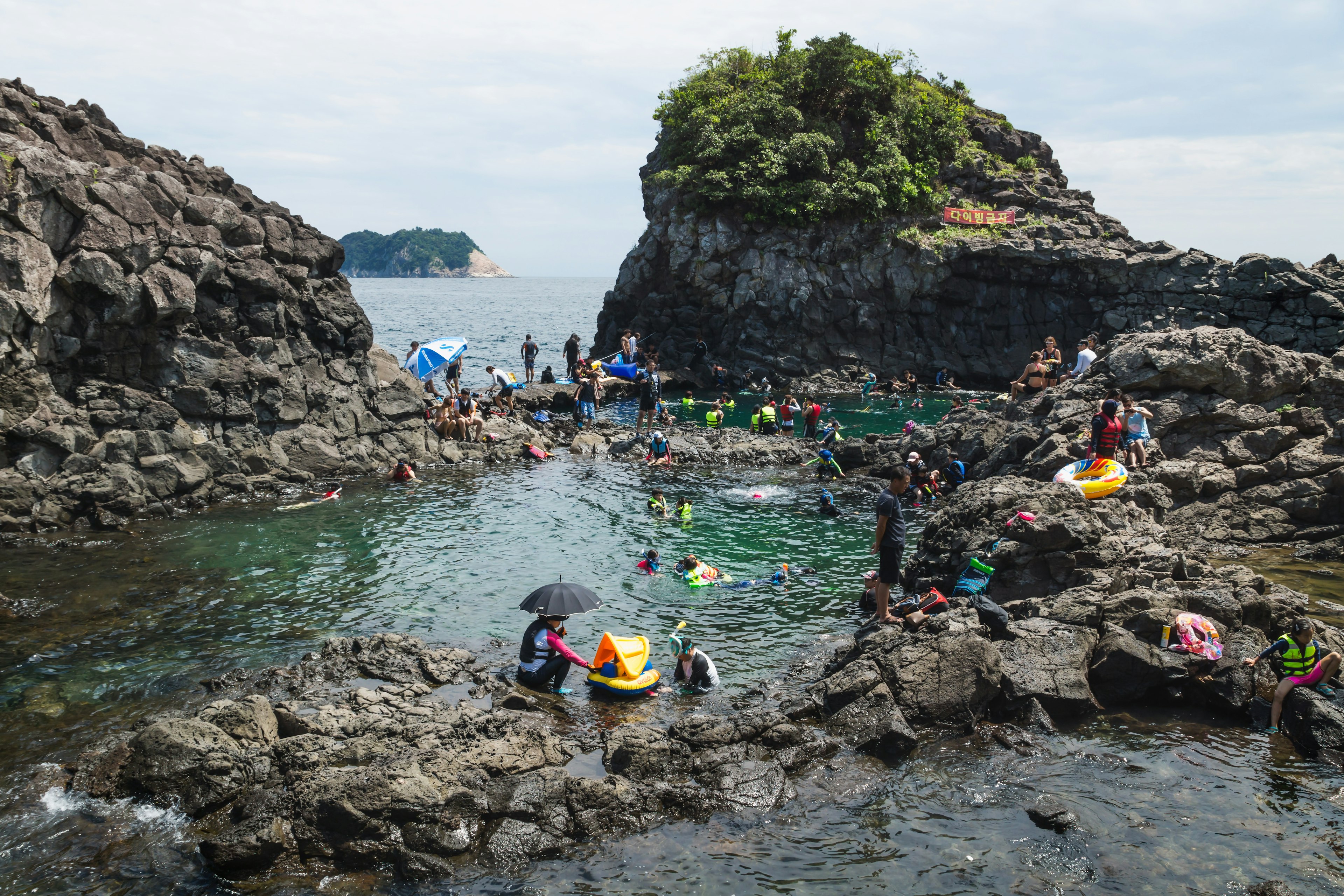 People swim in natural pools surrounded by rocks