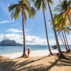 Woman on the beach amongst palm trees at El Nido, the Philippines