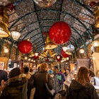 London, UK - Nov 8 2023: Covent Garden Market with Christmas decorations. Large bells and baubles hang from the roof. People are Christmas shopping at the Apple Market., License Type: media, Download Time: 2024-10-31T20:20:30.000Z, User: tasminwaby56, Editorial: true, purchase_order: 65050 - Digital Destinations and Articles , job: Online Editorial, client: Christmas Markets London, other: Tasmin Waby