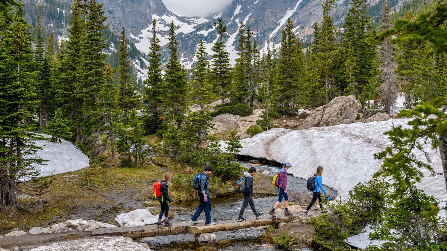 Estes Park, Colorado, USA - June 24, 2017: On a foggy spring day, a group of hikers walking cross a tree trunk bridge over Tyndall Creek on Emerald Lake Trail at base of Hallett Peak and Flattop Mtn.
708951949