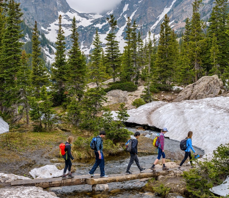Estes Park, Colorado, USA - June 24, 2017: On a foggy spring day, a group of hikers walking cross a tree trunk bridge over Tyndall Creek on Emerald Lake Trail at base of Hallett Peak and Flattop Mtn.
708951949