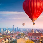 Hot air balloons flying over Vilnius during sunrise.
