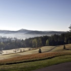 Early morning light pierces the mist and spreads across the Blue Ridge foothills.